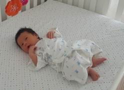 A baby lying on a bed
Description automatically generated
