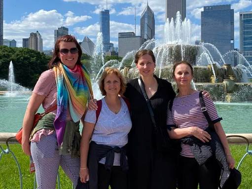 A group of women posing for a photo in front of a fountain

Description automatically generated