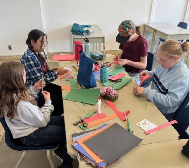 A group of girls sitting around a table with paper

Description automatically generated with low confidence