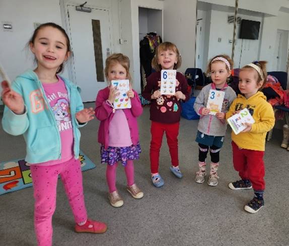 A group of children holding up cards

Description automatically generated