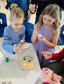 A group of kids painting eggs

Description automatically generated