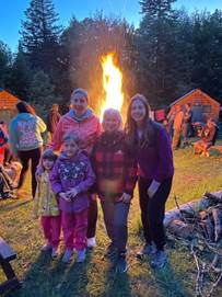 A group of people standing in front of a fire
Description automatically generated