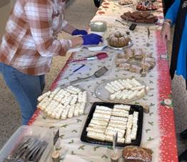 A group of people standing at a table with food

Description automatically generated