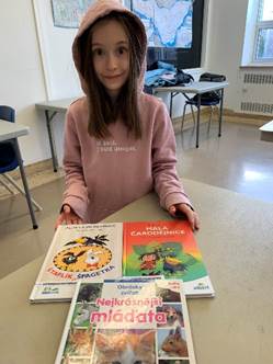 A child sitting at a table with books

Description automatically generated