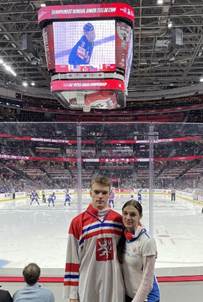 A person and person standing in a hockey arena
Description automatically generated