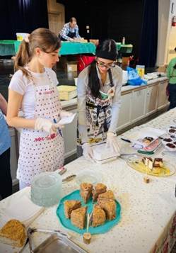 A couple of women in aprons standing in a kitchen

AI-generated content may be incorrect.